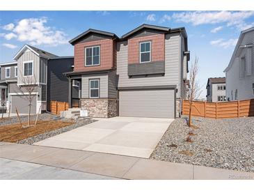 Charming two-story home with neutral siding, stone accents, and a two-car garage at 13531 E 99Th Pl, Commerce City, CO 80022