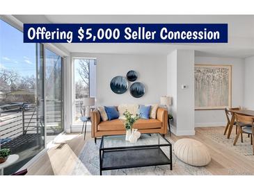 Bright living room with hardwood floors, modern furniture, and a large window at 1007 Chase St, Lakewood, CO 80214