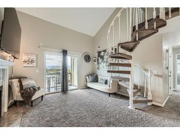Bright living room featuring a spiral staircase, balcony access with mountain views, and neutral decor at 10872 W Evans Ave # 3D, Lakewood, CO 80227