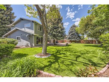 Secluded backyard featuring a lush green lawn, mature trees, and a cozy patio area at 6338 S Oneida Ct, Centennial, CO 80111