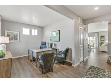 Bright home office with two chairs, stylish desk, hardwood floors, and lots of natural light at 4837 Cattle Cross Ln, Castle Rock, CO 80104