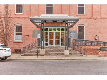 Building entrance with a glass entryway and stairs, set in a brick building with sidewalk and parking at 1143 Auraria Pkwy # 101, Denver, CO 80204
