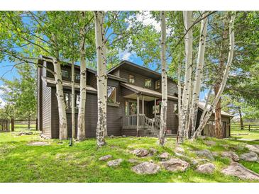 Charming brown two-story home with a green lawn and many aspen trees at 1927 Sunset Cir, Evergreen, CO 80439