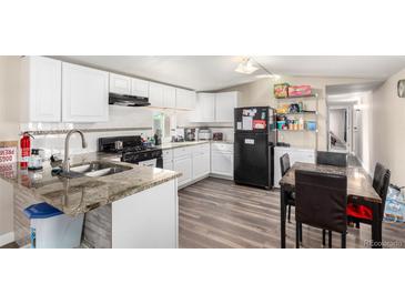 Bright kitchen featuring granite countertops, white cabinetry, and stainless steel appliances, ideal for cooking and entertaining at 119 Yakima St, Lochbuie, CO 80603