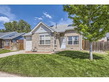Charming brick home featuring a well-manicured lawn, attached garage, and inviting front entrance at 4912 Altura St, Denver, CO 80239