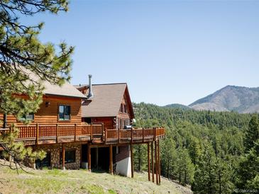 Wood cabin featuring a spacious deck with scenic views of the surrounding forest and mountains at 750 Cougar Dr, Boulder, CO 80302