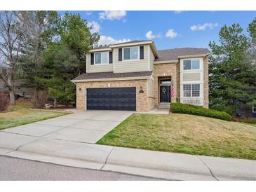 Charming two-story home with brick accents, a well-manicured lawn, and a two-car garage at 8114 Briar Ridge Dr, Castle Pines, CO 80108