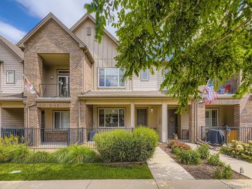 Charming townhome with a brick facade, covered porch, iron railing, and beautiful landscaping at 600 E Dry Creek Pl, Littleton, CO 80122