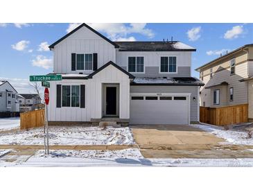 Beautiful two-story home featuring a two-car garage, and modern farmhouse design with white and gray accents at 9153 Truckee Ct, Commerce City, CO 80022
