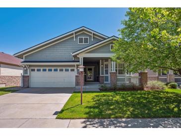 Charming home featuring manicured lawn, covered porch, and attached two-car garage at 7852 S Addison Way, Aurora, CO 80016
