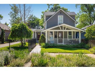 Charming gray two-story home with a manicured front yard, white picket fence, and inviting porch at 3943 Newton St, Denver, CO 80211