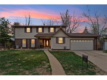 Charming two-story home boasts a well-manicured lawn, mature trees, and a welcoming entrance at 2410 S Lima St, Aurora, CO 80014