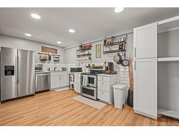 Bright kitchen with stainless steel appliances, white cabinetry, and stylish open shelving for storage at 12112 Melody Dr # 302, Denver, CO 80234