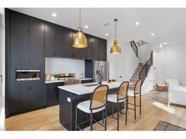 Modern kitchen featuring dark cabinetry, quartz countertops, stainless steel appliances and pendant lighting at 1250 Yates St, Denver, CO 80204