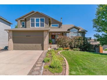 Charming two-story home with attached garage, manicured lawn, and vibrant landscaping under a clear blue sky at 6590 S Tabor St, Littleton, CO 80127