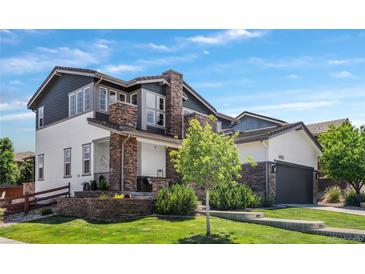 Charming two-story home with a manicured lawn, stone accents, and a covered front porch at 14110 Pastel Ln, Parker, CO 80134