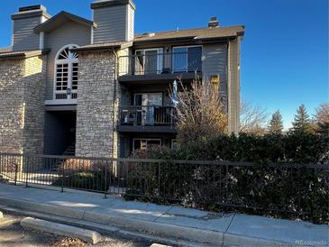 Charming condo building with stone facade, balconies, and mature landscaping offers a inviting curb appeal at 2575 S Syracuse Way # M108, Denver, CO 80231