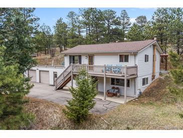 Charming exterior view of a two story house with a deck, a large lot, and a three car garage at 30313 Arena Dr, Evergreen, CO 80439