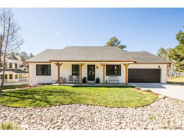 Charming single-story home featuring a well-manicured front yard and a welcoming covered porch with seating at 1288 Gambel Oaks Dr, Elizabeth, CO 80107
