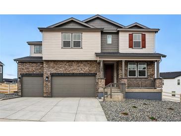 Beautiful two-story home with stone accents, gray siding, a covered porch, and a three-car garage at 1667 Fox Trotter Pt, Castle Rock, CO 80104
