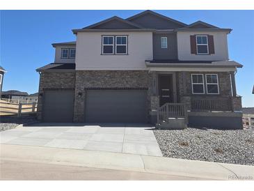 Beautiful two-story home with a stone facade and a three-car garage at 1667 Fox Trotter Pt, Castle Rock, CO 80104