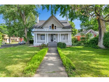 Charming two-story home boasts a welcoming front porch and well-manicured lawn with mature trees at 7011 Grandview Ave, Arvada, CO 80002