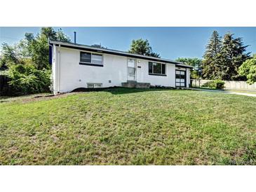 Charming single-story home featuring a well-maintained lawn and a classic white brick facade at 7704 Newland St, Arvada, CO 80003