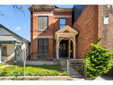 Charming two-story brick home featuring a welcoming front porch and manicured garden at 2318 Arapahoe St, Denver, CO 80205