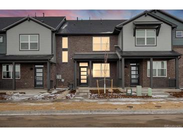 Charming townhome featuring a brick facade, covered porch, and modern door design, with a neatly landscaped front yard at 762 N Tempe St, Aurora, CO 80018