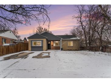 Charming single-story home showcasing a brick exterior, grey accents, and a snow-covered front yard at 1534 Rosemary St, Denver, CO 80220
