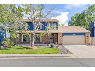 Charming two-story home featuring a brick and blue exterior with a well-manicured lawn and a cozy covered front porch at 3238 W 11Th Avenue Pl, Broomfield, CO 80020