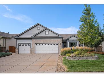 Charming home featuring a well-maintained front yard, brick accents, and a spacious three-car garage at 21064 Woodside Ln, Parker, CO 80138