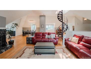 Cozy living room with a red leather sofa, hardwood floors, and views of the unique spiral staircase at 1165 N Pennsylvania St # 3B, Denver, CO 80203
