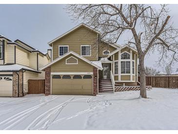 Tan two-story house with a large window and snow covered lawn at 1218 Ascot Ave, Highlands Ranch, CO 80126