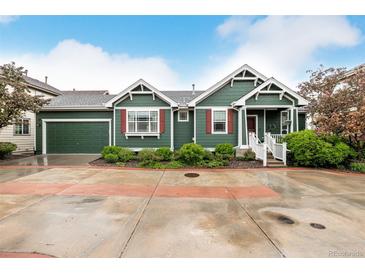 Charming green home with red shutters, a well-maintained lawn and an attached two-car garage at 13263 Niwot Trl, Broomfield, CO 80020