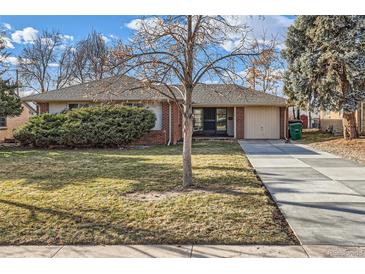 Charming brick home featuring a well-manicured lawn and a long, paved driveway leading to an attached garage at 2675 N Saint Paul St, Denver, CO 80205