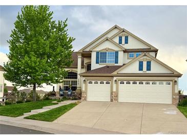 Charming two-story home featuring a three car garage, blue shutters, and professionally landscaped yard at 22962 Briar Leaf Ave, Parker, CO 80138