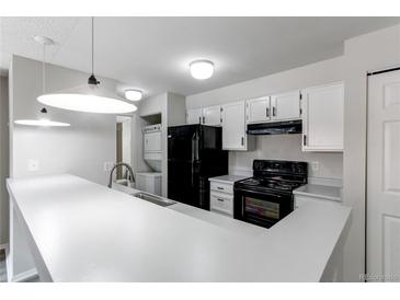Bright kitchen features black appliances, white cabinets, breakfast bar and stacked washer/dryer at 4899 S Dudley St # 15B, Littleton, CO 80123