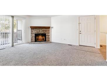 Cozy living room featuring a brick fireplace and sliding glass door to balcony at 7820 W 87Th Dr # A, Arvada, CO 80005