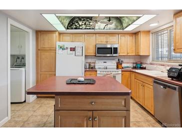 Bright kitchen with a central island, stainless steel appliances and a unique ceiling light at 9019 E Oxford Dr, Denver, CO 80237