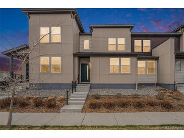 Modern home exterior with neutral siding, a stone base, and a short staircase leading to the front door at 4755 Memphis St # 2, Denver, CO 80239
