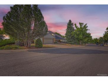 Charming two-story home featuring a well-manicured lawn and mature trees against a vibrant evening sky at 3777 S Walden St, Aurora, CO 80013