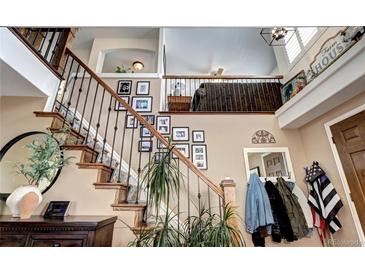 Charming entryway with wood stairs, iron railing, and decorative wall art leading to upper level at 4907 Fenwood Dr, Highlands Ranch, CO 80130