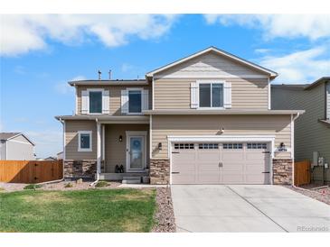 Charming two-story home featuring stone accents, a two-car garage, and a well-manicured lawn at 14836 Jersey Dr, Mead, CO 80542