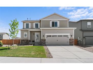 Charming two-story home with a well-manicured lawn and a two-car garage and stone accents at 14836 Jersey Dr, Mead, CO 80542