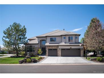 Stunning two-story home featuring stone accents, a three-car garage, and beautifully landscaped front yard at 9445 Aspen Hill Cir, Lone Tree, CO 80124