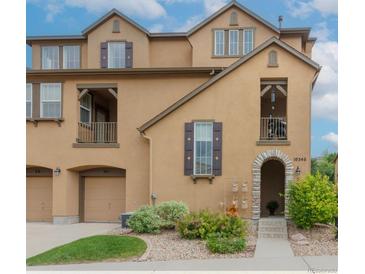 Inviting exterior elevation of a two-story townhome with a stone archway entrance and manicured landscaping at 10546 Graymont Ln # D, Highlands Ranch, CO 80126