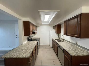 Well-lit kitchen with granite countertops, tile floors and stainless steel appliances at 2929 W Floyd Ave # 217, Denver, CO 80236