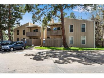 Two-story condo buildings featuring balconies, wooden fences, and assigned parking with mature trees at 8050 Niwot Rd # 40, Niwot, CO 80503