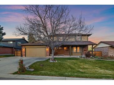 Charming two-story home with a lush front lawn, mature trees, and a two-car garage at 5270 Tabor St, Arvada, CO 80002